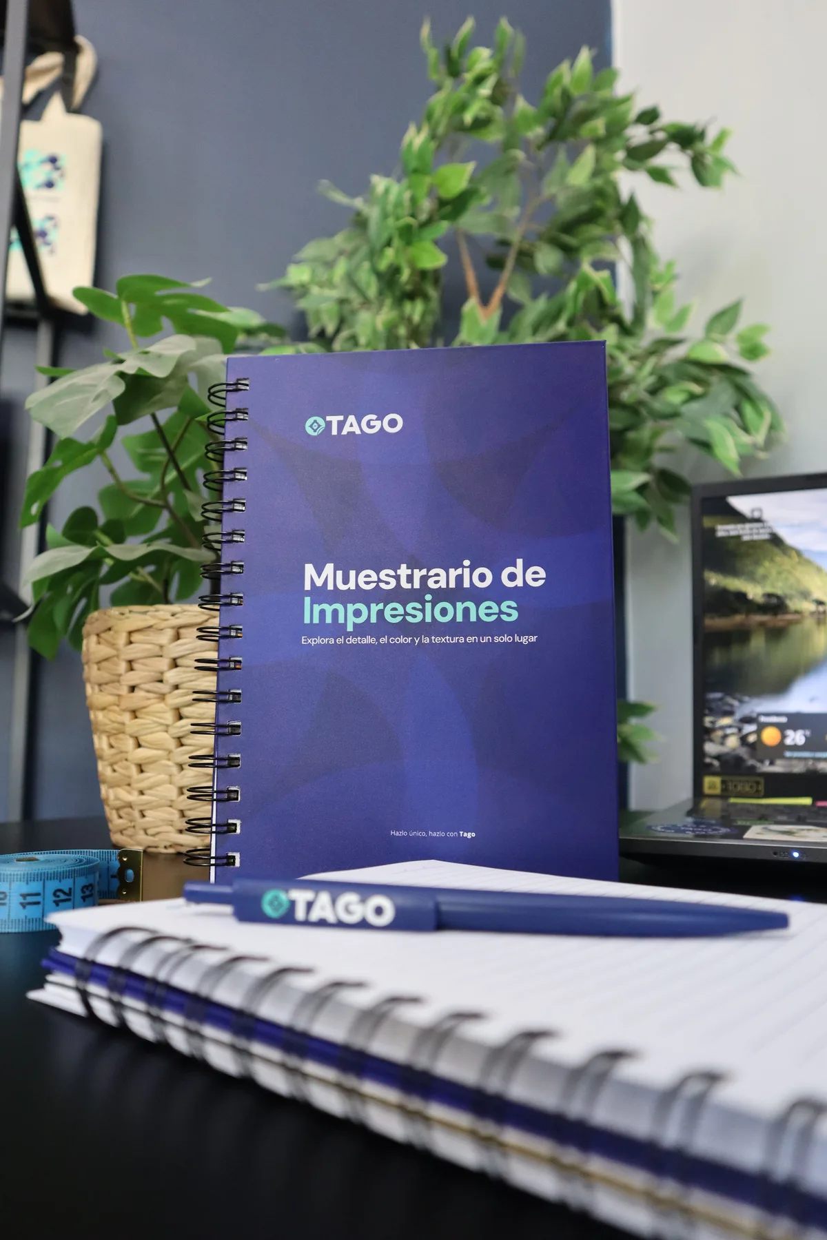 Muestrario de impresiones TAGO junto a un bolígrafo con logo