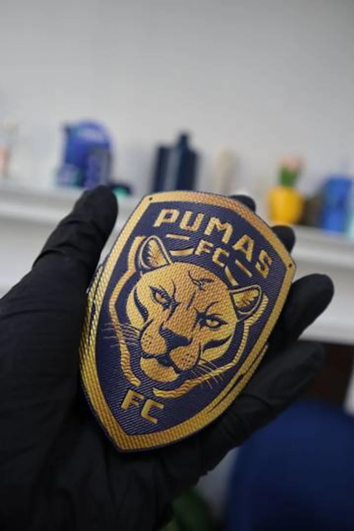 Insignia bordada de un club deportivo sostenida con la mano